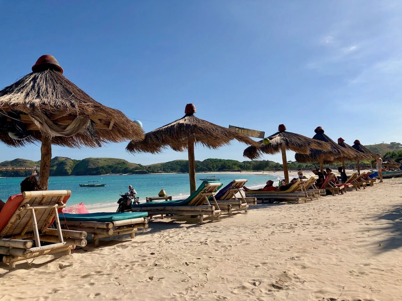 row of beach chairs with straw umbrellas looking at the beach in Lombok