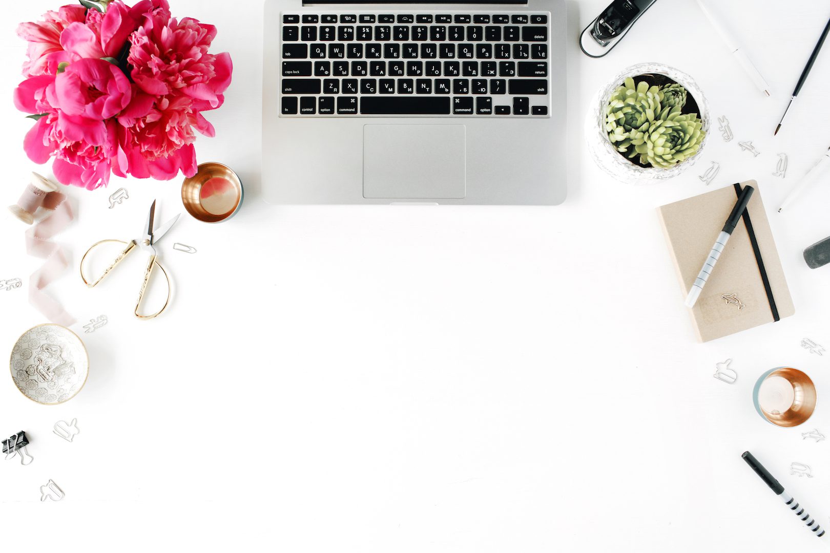 A white desk with a laptop and pink flowers