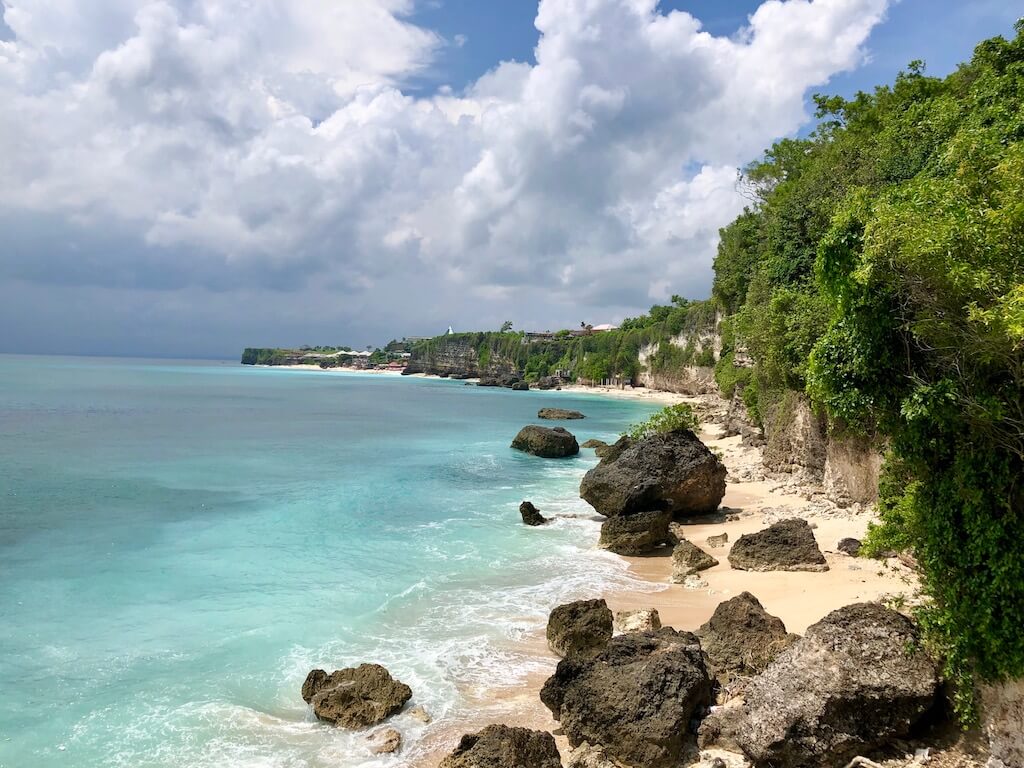 Uluwatu Travel Guide, limestone cliffs overlooking a white sand beach with blue water