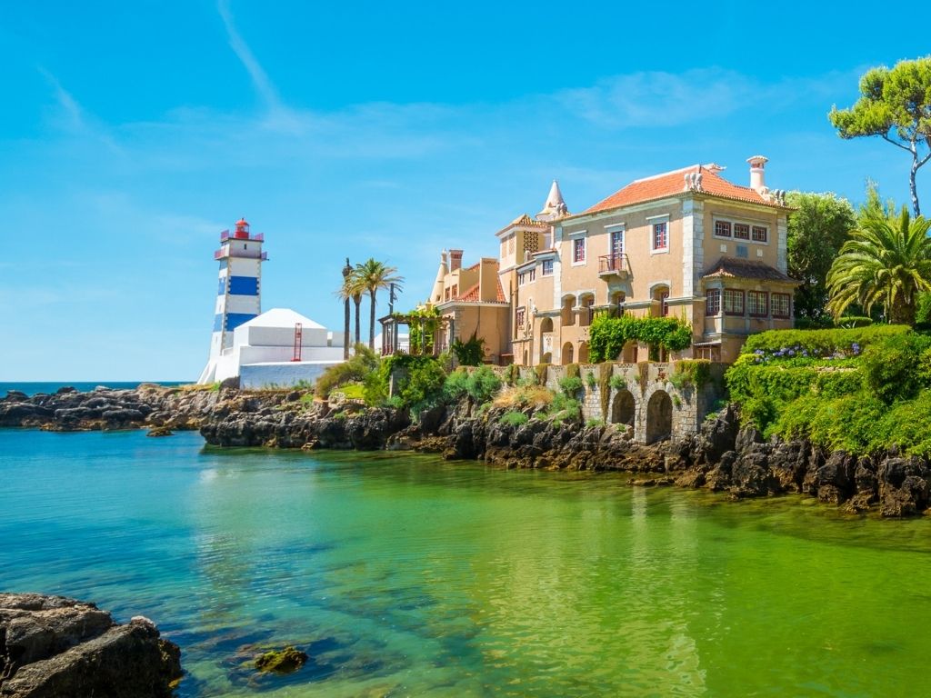 Santa Marta Lighthouse in Cascais above teal blue water