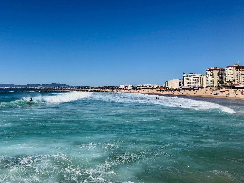 A surfer catching a wave off the coast of Costa da Caparica