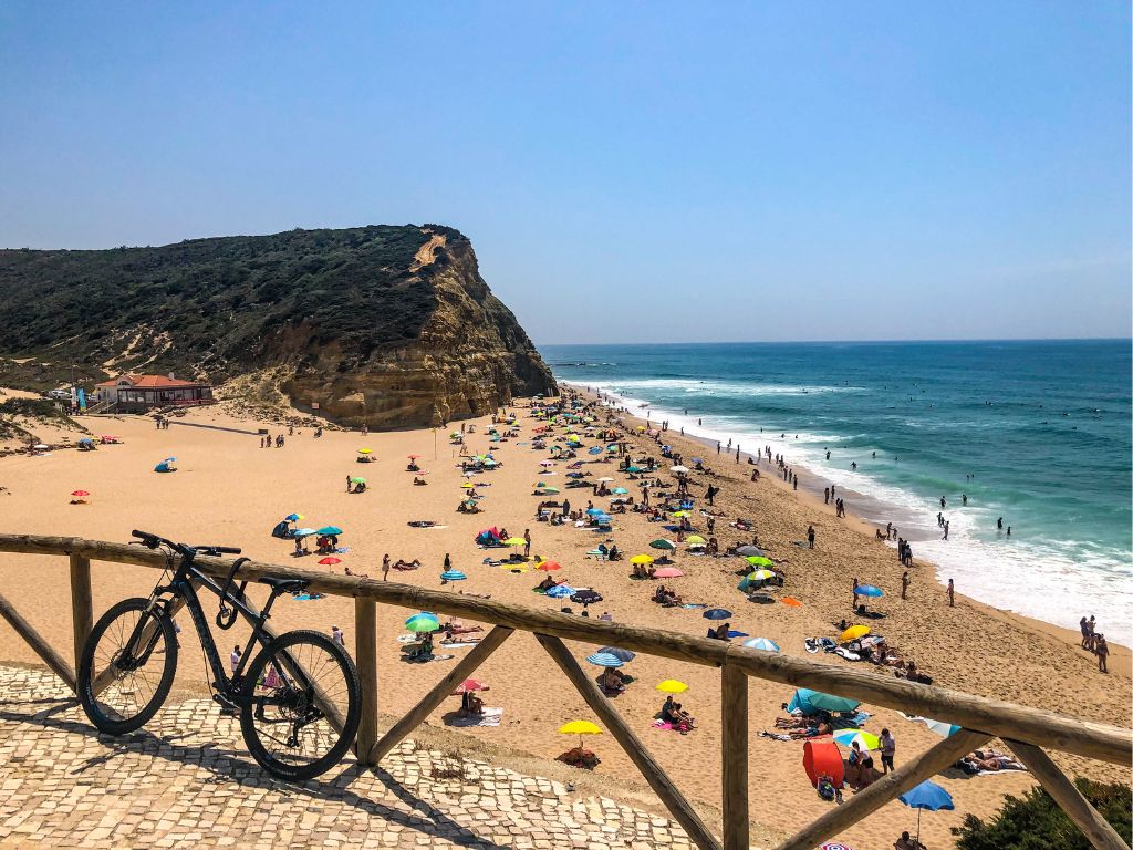 A bicycle tied to a railing overlooking Praia de Sao Juliao in Ericeira