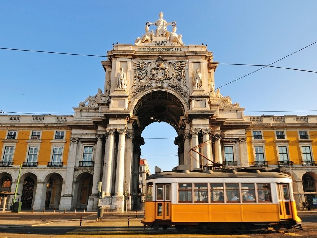 A yellow tram passing the Arco da Rua Augusta in downtown Lisbon
