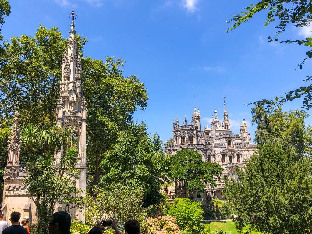 Quinta da Regaleira palace with a tower in the foreground and green trees surrounding