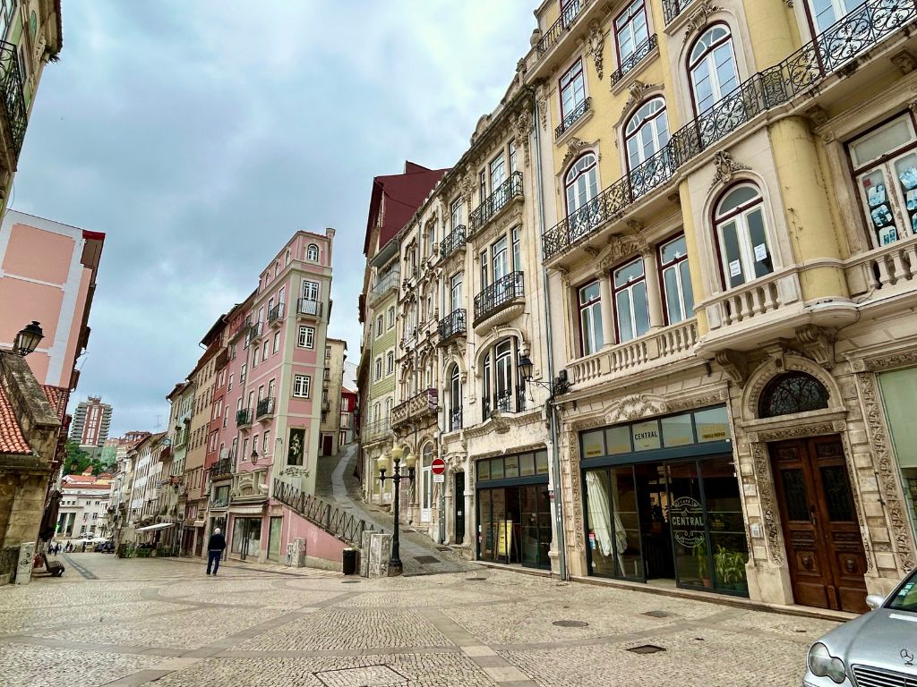 A beautiful street to see on your 1 Day in Coimbra Itinerary. This street has a narrow pink building and rows of old buildings with colorful facades.